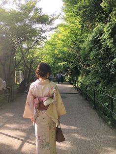 a woman in a kimono walking down a path