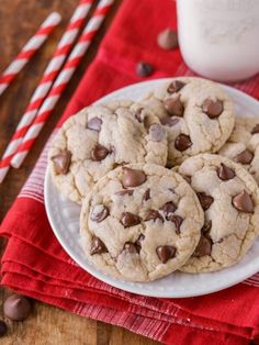 chocolate chip cookies on a white plate next to a glass of milk