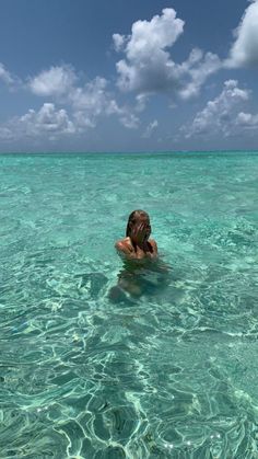 a woman swimming in the ocean with her head above water's surface and clouds overhead