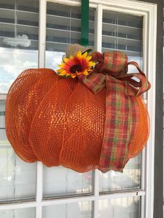 an orange pumpkin with a sunflower on it's head hanging from a window