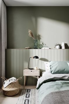 a bed room with a neatly made bed next to a night stand and a basket