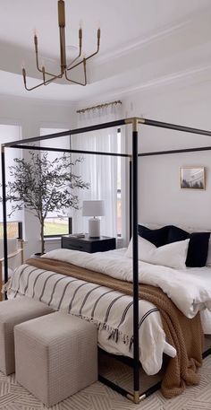 a bedroom with a four poster bed and white walls, carpeted flooring and a chandelier hanging from the ceiling