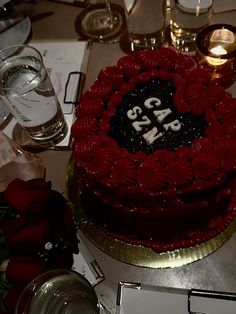 a red and black cake sitting on top of a table next to wine glass glasses