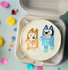 two decorated cakes in a plastic container on a table