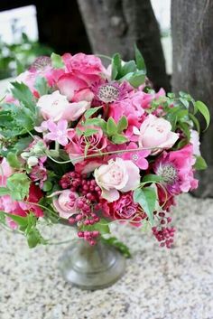 a vase filled with pink flowers and greenery on top of a stone countertop