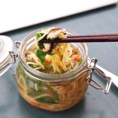 a glass jar filled with noodles and vegetables