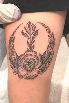 a black and white photo of a woman's thigh with a flower tattoo on it