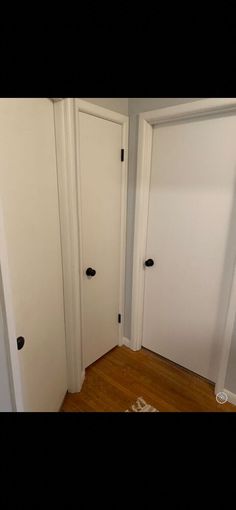 two white doors are open in the corner of a room with wood floors and hard wood flooring