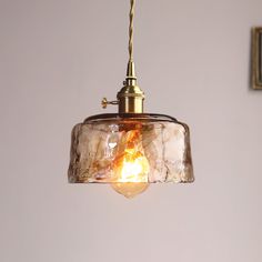 a light that is hanging from a ceiling with a glass shade on top of it