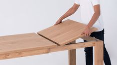 a man standing next to a table with a piece of wood on top of it