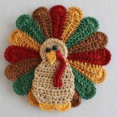 a crocheted turkey ornament is shown on a white surface with red, green and yellow accents