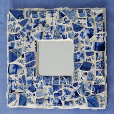 a blue and white mosaic tile with a square mirror in the middle on a blue background