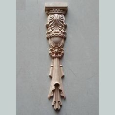 an intricately carved wooden corbge on the side of a gray wall with white paint