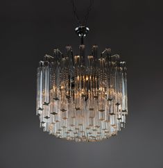 a crystal chandelier hanging from the ceiling in a room with dark walls and flooring