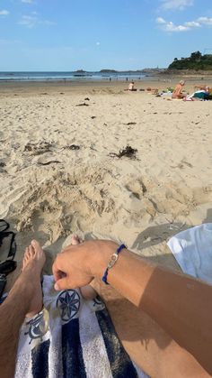 a man laying on top of a beach under a blue and white towel next to the ocean