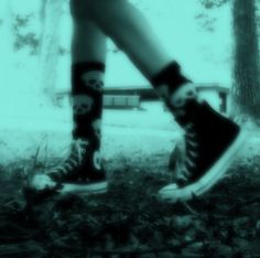 black and white photograph of someones legs with skulls on them, walking in the woods