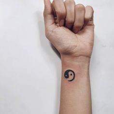 a person's arm with a small tattoo on the wrist that has a yin symbol