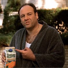 a man in a bathrobe points to an orange juice carton