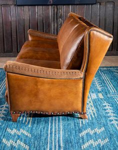 a brown leather chair sitting on top of a blue rug