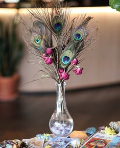 a vase filled with flowers and feathers on top of a table