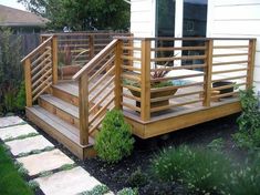 a wooden deck with planters on it and steps leading to the front door area