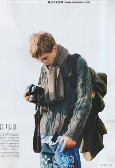 a young man holding a camera and looking at it