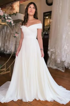 a woman in a white dress standing on a wooden floor