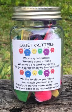 a jar filled with colorful candies sitting on top of a wooden table next to grass