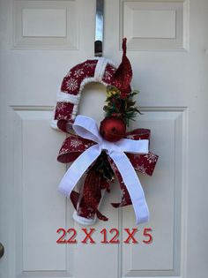 a red and white christmas wreath hanging on a door with the number 22 attached to it