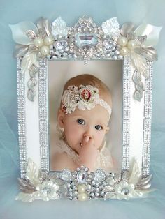 a baby in a frame with pearls and flowers