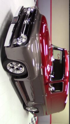 the front end of a red truck parked in a room with checkered flooring