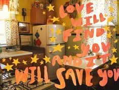 a kitchen with yellow walls and stars painted on the wall above the stove, refrigerator and sink