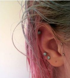 a woman with pink hair has three piercings on her ear