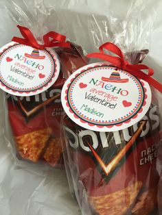 two bags of chips wrapped in plastic wrappers with red bows on them, sitting next to each other