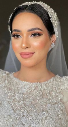 a woman in a wedding dress with a veil on her head and wearing a tiara