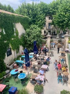 people are sitting at tables in an outdoor patio area with umbrellas and table cloths