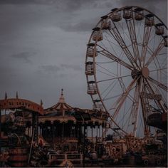 an amusement park with a ferris wheel and other rides in the background on a cloudy day