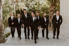 a group of men standing next to each other wearing black suits and white shirts on their wedding day