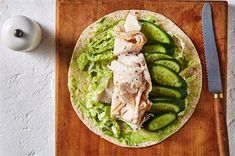 a tortilla with cucumbers and fish on it next to a knife