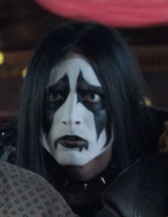 a man with black hair and white face paint