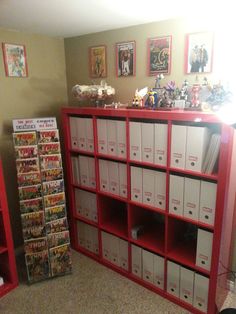 a red bookcase filled with comic books next to a wall full of comics and action figures