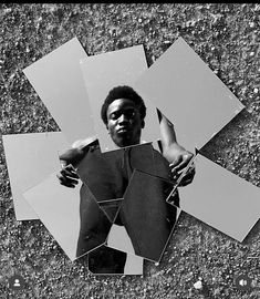 a black and white photo of a man holding up mirrors