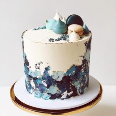 there is a blue and white cake with shells on the top, sitting on a plate