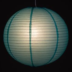 a large white paper lantern hanging from a black ceiling in the dark with no lights