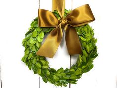 a green wreath with gold ribbon hanging on a white door