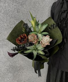 a woman holding a bouquet of flowers in her hand and wearing a black dress with fringes on it