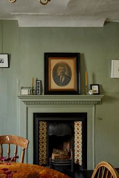 a room with a fire place and pictures on the wall above it, along with a table and chairs