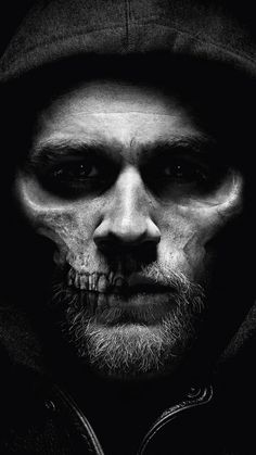 a black and white photo of a man wearing a hoodie with his face painted like a skull