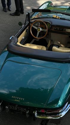 the interior of a green sports car is seen in this image, with people standing around it