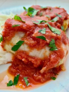 some food is sitting on a plate with sauce and parmesan cheese, as well as green leaves